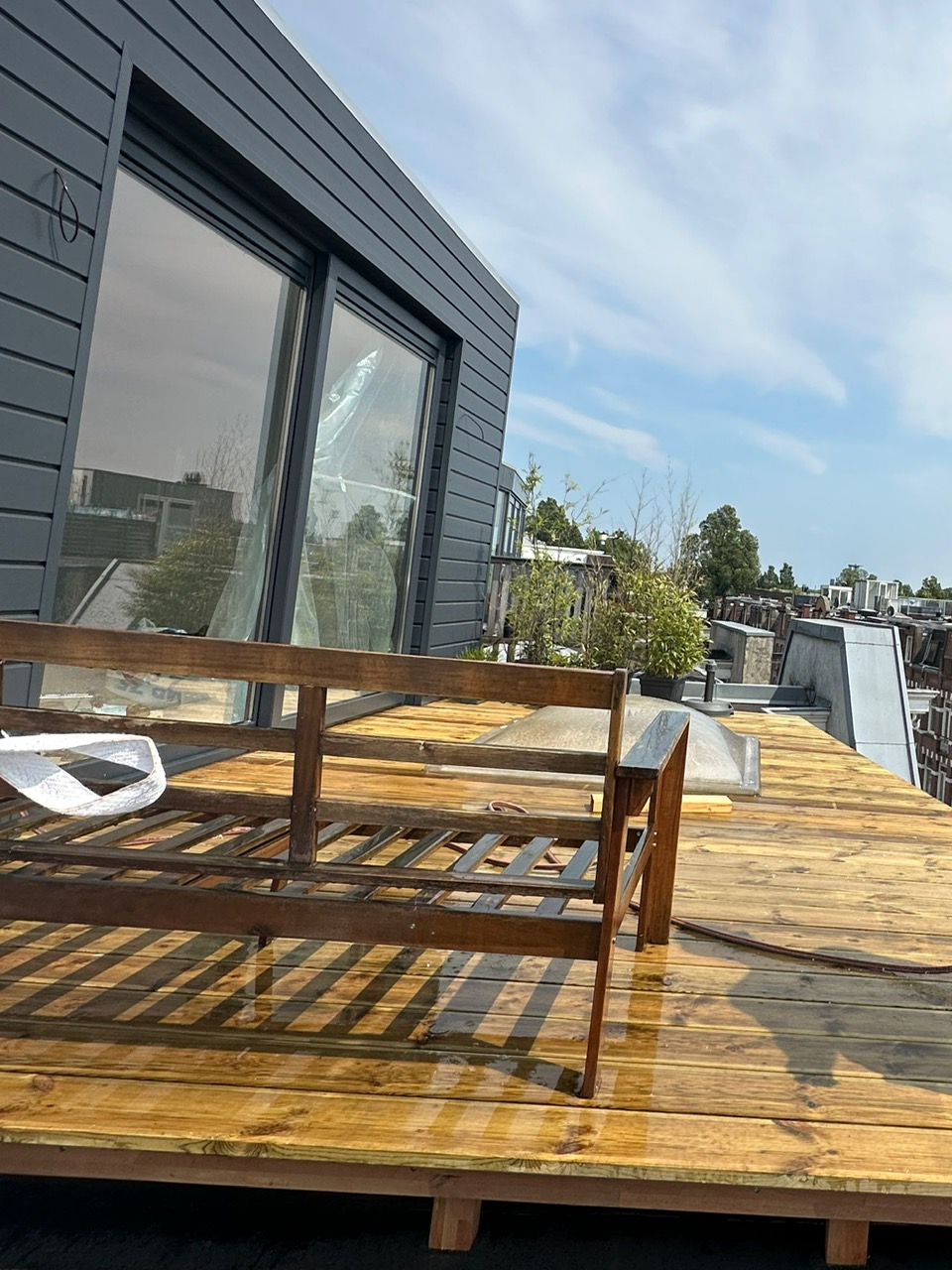 Dakopbouw met donkere gevelbekleding en houten dakterras in Amsterdam-Oost