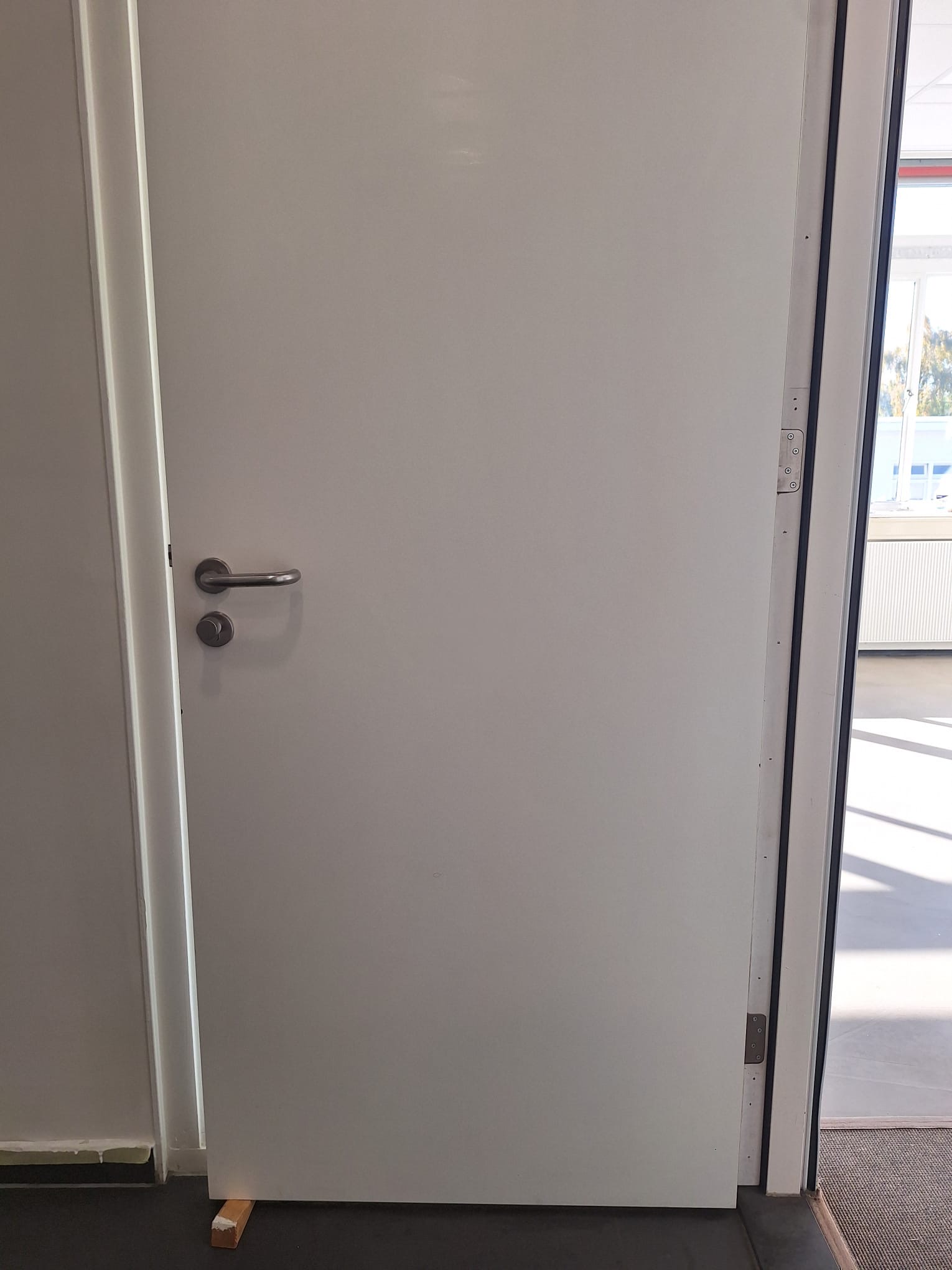 Detailfoto van een binnendeur met deurkruk in kantoorpand Schinkelhaven, Amsterdam
