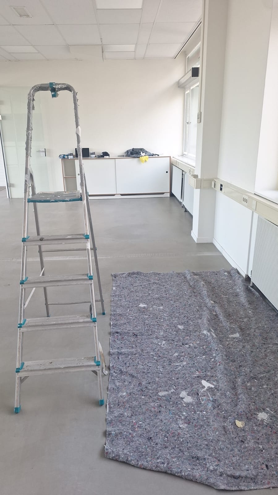 Kantoorruimte met schildermaterialen en afgedekte vloer in Schinkelhaven, Amsterdam
